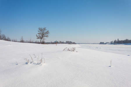 shot of snowy landscape with clear sky and frozen river