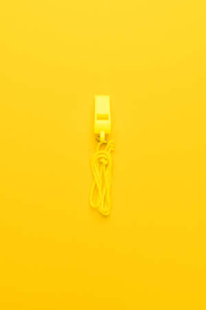plastic referee whistle on the yellow backgroundの写真素材