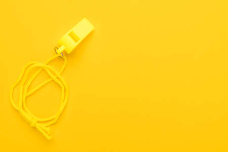 Plastic referee whistle on the yellow background with copy spaceの写真素材