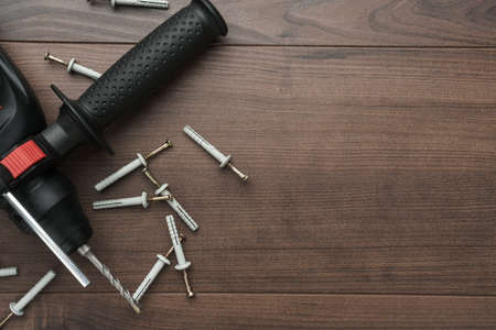 hammer drill and dowels on the wooden background with copy space