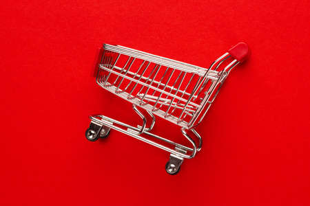 close-up photo of shopping trolley on red background. minimalistic photo of pushcartの写真素材