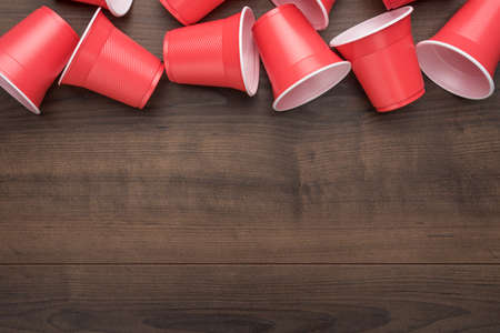 disposable plastic cups on the wooden background. top view of used plastic cups on the table. end of...