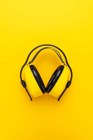 hearing protection industrial ear muffs on yellow background. vertical shot of yellow ear muffsの写真素材