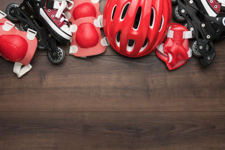 Roller skates and body parts protection on brown table with copy space