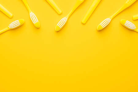 Many new plastic toothbrushes on the yellow  with copy spaceの写真素材