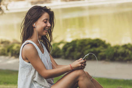 Portrait of young woman listening to the music on the phone in the park