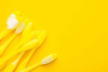 Many new plastic yellow toothbrushes on the yellow  with copy spaceの写真素材