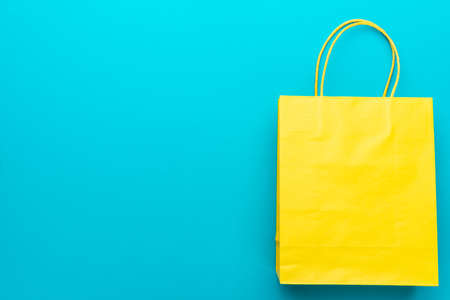 shopping paper bag on the turquoise blue background. flat lay photo of yellow bag. summer sale...