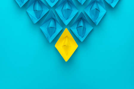 Yellow paper ship ahead of blue ones leadership concept over blue