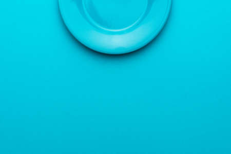 Minimalist  of round ceramic plate over turquoise blue  with copy space.の写真素材