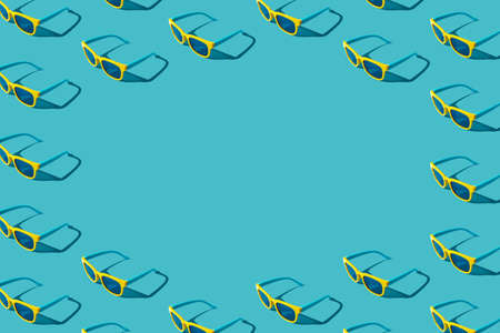 Stylish pattern of plastic sunglasses on turquoise blue background with copy space. Minimalist...