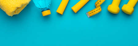 Flat lay photo of fitness equipment over turquoise blue backgound. Top view of yellow street workout...