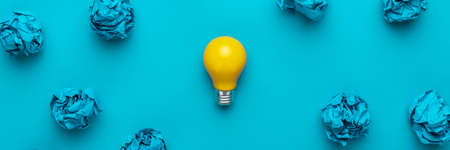 New idea concept with crumpled office paper and light bulb. Top view of great business idea concept over blue background. Creative solution during brainstorming session concept.の写真素材