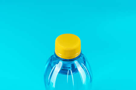 Minimalist photo of water bottle with copy space. Plastic water bottle with yellow cap on the blue background.の写真素材