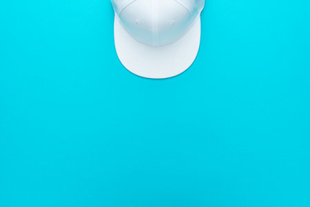 Top view of baseball cap over torquoise blue background. Minimalist flat lay photo of white cap with copy space.の写真素材