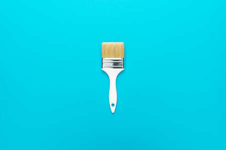 Paint brush on the turquoise blue background. Minimalist photo of white brush central composition.の写真素材