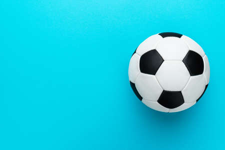 Top view photo of white and black soccer ball as football concept . Minimalist flat lay image of leather football ball over blue turquoise background with copy space and right side composition.の写真素材