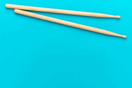 Minimalist photo of pair of wooden drumsticks on turquoise blue background. Flat lay top-down composition of drumsticks with copy space.の写真素材