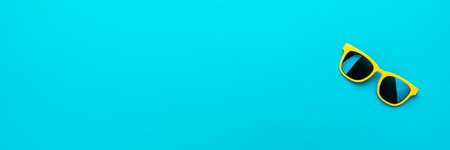 Minimalist photo of stylish yellow sunglasses as summer concept. Close-up image of vivid color plastic sunglasses on turquoise blue background with copy space.の写真素材