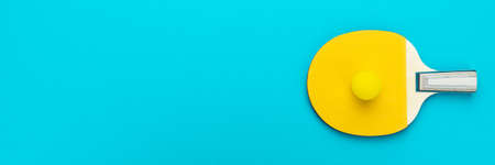 Racket and ball for table tennis on turquoise blue background. Flat lay image of table tennis paddle with a ball. Minimalist photo of yellow ping-pong equipment.の写真素材