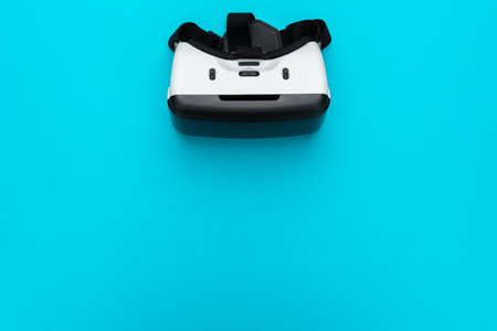 Virtual reality headset on turquoise blue background. Top view of VR helmet with copy space....