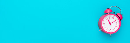 Pink alarm clock over turquoise blue background with copy space. Time management concept.