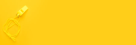 Plastic referee whistle on the yellow background with copy space