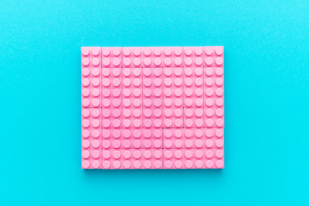 Central composition of plastic building blocks on turquoise blue background with copy space....