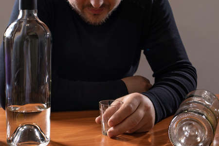A man in alcoholic intoxication holds a glass of alcohol. Alcoholism, addiction, deliriumの写真素材