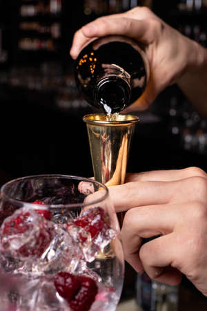 The bartender prepares a cocktail in the restaurant bar. The process of pouring alcohol into a glass.の写真素材
