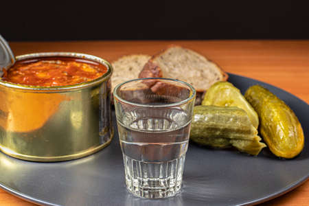 Drinks and snacks. A glass of vodka, sprats, bread and pickles.の写真素材