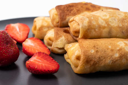 Homemade pancakes with strawberries on a black plate. Baking at home, delicious breakfast.