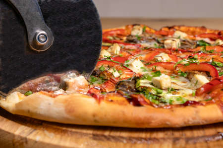 The process of slicing the pizza into pieces with a round roller knife. Cooking fragrant Italian pizza.の写真素材