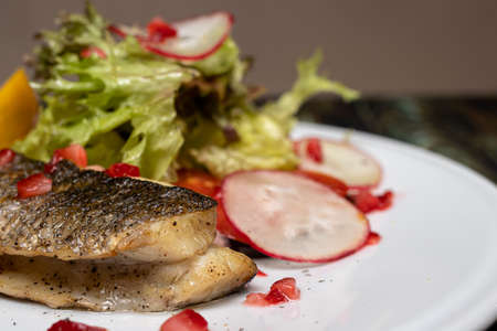 Baked sea fish with vegetables radish, lettuce, lemon and tomatoes. Good proper nutrition, weight loss, maintaining the health of the body. Keto diet, gluten-free diet.の写真素材