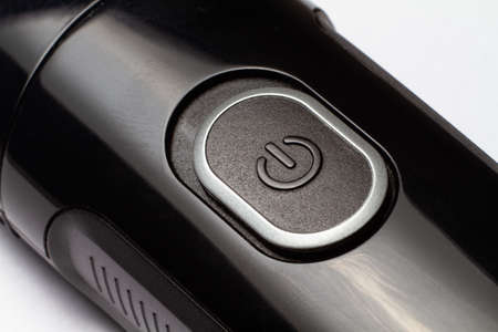 The button is on and off on a black electric razor trimmer on a white background