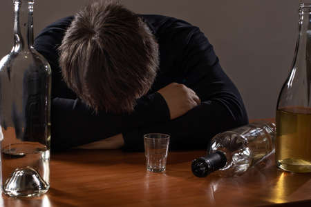 A man in alcoholic intoxication holds a glass of alcohol. Alcoholism, addiction, deliriumの写真素材
