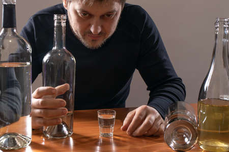 A man in alcoholic intoxication holds a glass of alcohol. Alcoholism, addiction, deliriumの写真素材
