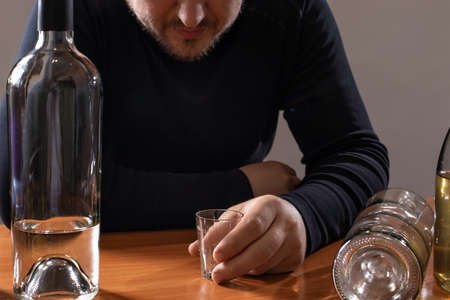 A man in alcoholic intoxication holds a glass of alcohol. Alcoholism, addiction, deliriumの写真素材