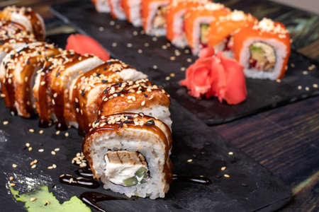 Sushi and rolls on a black background. Japanese food, seafood and raw fish with wasabi sauce