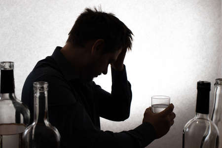 A man and a glass of vodka. Alcoholism, alcohol addiction, delirium tremens.