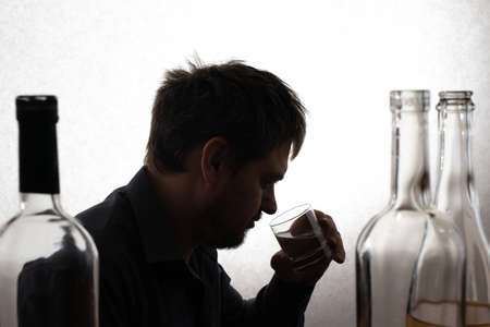 A man and a glass of vodka. Alcoholism, alcohol addiction, delirium tremens.
