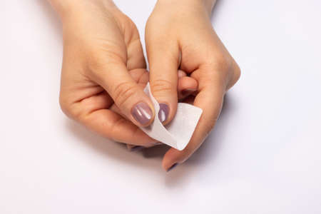 Hands with purple gel polish. Removing the topcoat gel polish from the sticky layer. Lint-free cloth. Manicure at home.の写真素材