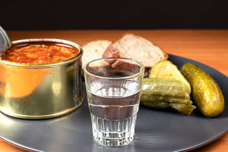 Drinks and snacks. A glass of vodka, sprats, bread and pickles.の写真素材
