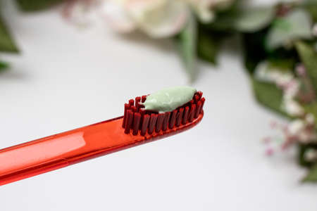Red toothbrush with green natural toothpaste on a white background.の写真素材