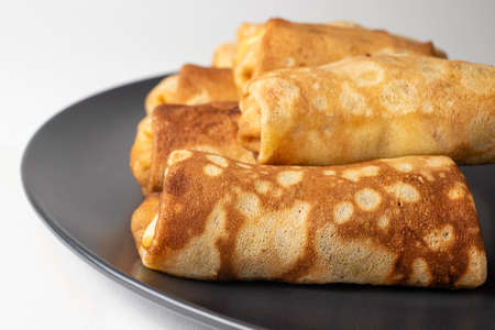 Wheat flour pancakes on a black plate on a white background.の写真素材