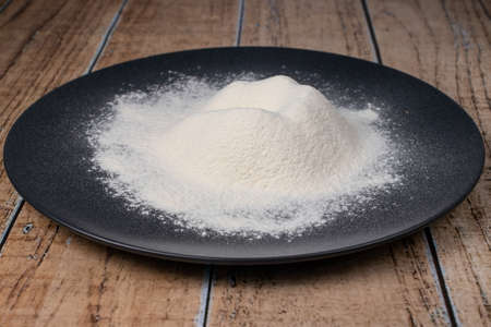 Wheat white flour on a black plate. Making bread and baked goods. Cooking at home.の写真素材