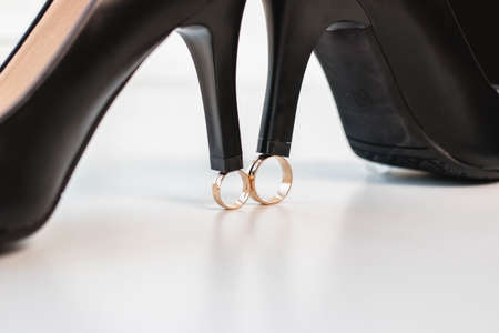 Wedding rings of the bride and groom and black shoes on a white background. Wedding day.