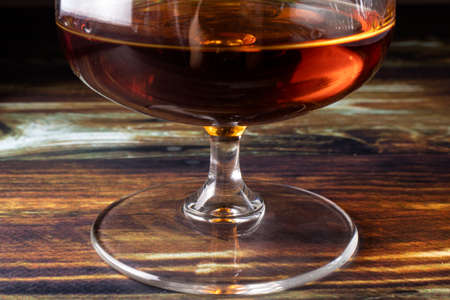 Glass with cognac on a wooden background. Dear elite alcohol.