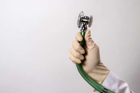 Green stethoscope. A doctor in a white medical uniform and gloves holds a stethophonendoscope.