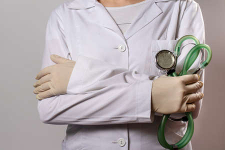 Green stethoscope. A doctor in a white medical uniform and gloves holds a stethophonendoscope.の写真素材
